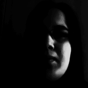 A dark and moody black and white photograph of Steffi's face.